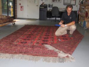 A technician carefully inspecting a large oriental rug for cleaning or repair at Ziegler Preservation Cleaning in Danbury, CT
