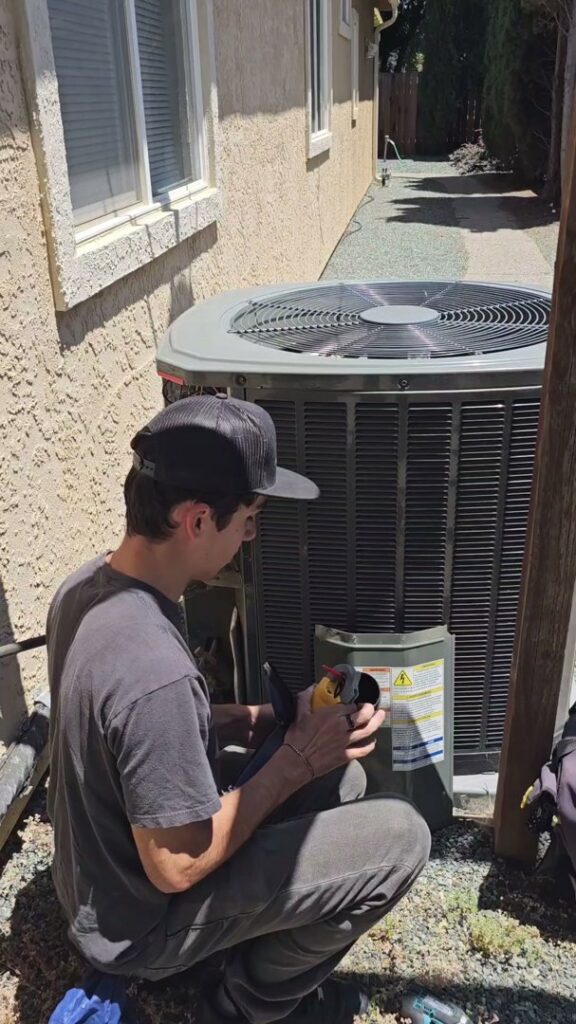 A technician inspecting or performing service on an outdoor air conditioning unit for Ecology Air Innovations in Sacramento, CA.