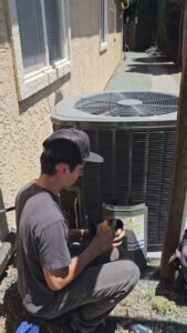 A technician inspecting or performing service on an outdoor air conditioning unit for Ecology Air Innovations in Sacramento, CA.