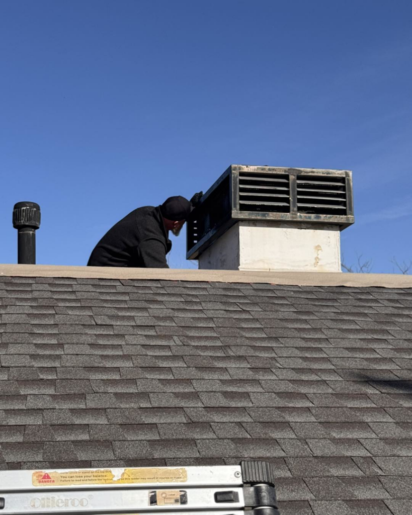 An Absolute Pest Solutions technician inspecting a roof vent for wildlife or pest entry points on a home in Piedmont, OK.