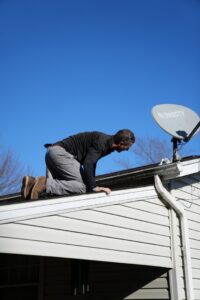 A pest control technician inspecting a roofline and gutter for potential pest or wildlife entry points at Complete Pest Solutions of Canton in North Canton, OH.