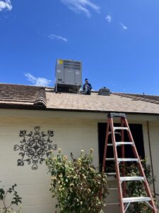 An Arrow Pro Services technician inspecting a newly installed rooftop HVAC unit on a residential home in Gilbert, AZ