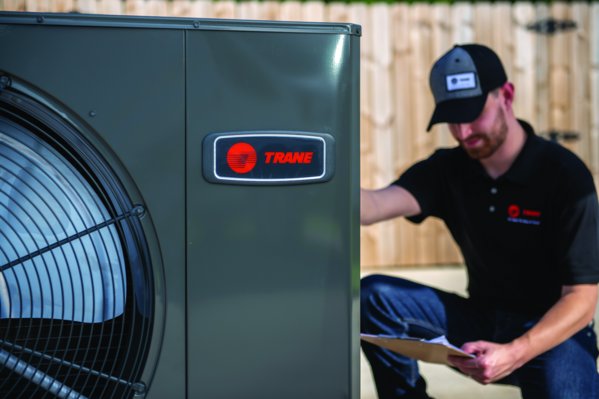 A technician inspecting a Trane outdoor AC unit during a service visit by Bree HVAC Contractor in Cedar Park, TX.