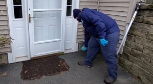 A technician inspecting and treating a doorway for pests at a residential property for Richmond Pest Control in Richmond, KY.