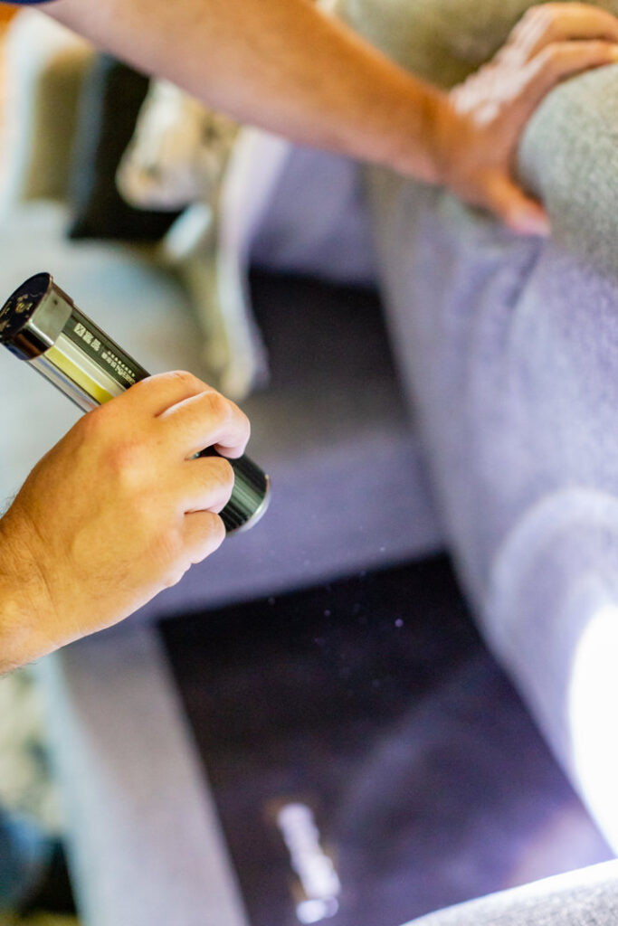 A pest control technician inspecting under furniture with a flashlight for pests at Advanced Pest Control Solutions in Youngstown, OH.