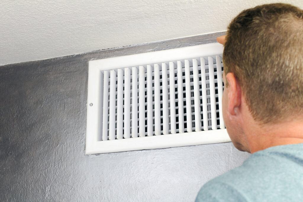A technician inspecting a wall air vent, demonstrating an HVAC inspection by Wright Way Air Duct Cleaning in Streamwood, IL