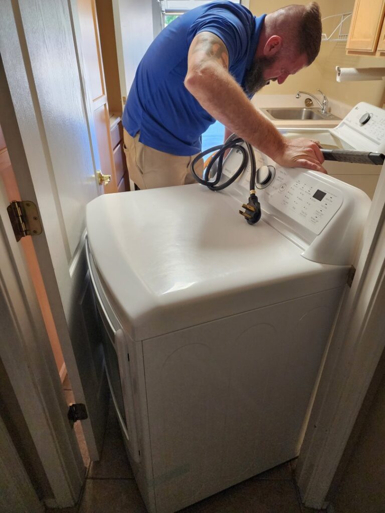 A Duct Dudes technician inspecting a washing machine, likely in preparation for dryer vent service in Scottsdale, AZ.