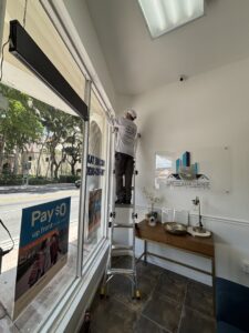A technician on a ladder inspecting a window area for pest control by PNP Pest Solutions LLC in Miami, FL.