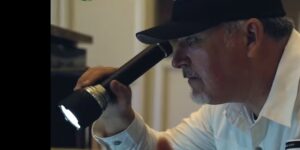A Preferred Choice Pest Control technician performing an inspection with a flashlight in Surprise, AZ.