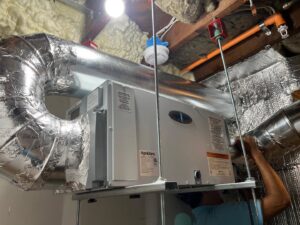 A technician installing an AprilAire HVAC unit with insulated ductwork for Enviromax Heating & Cooling in Peekskill, NY.