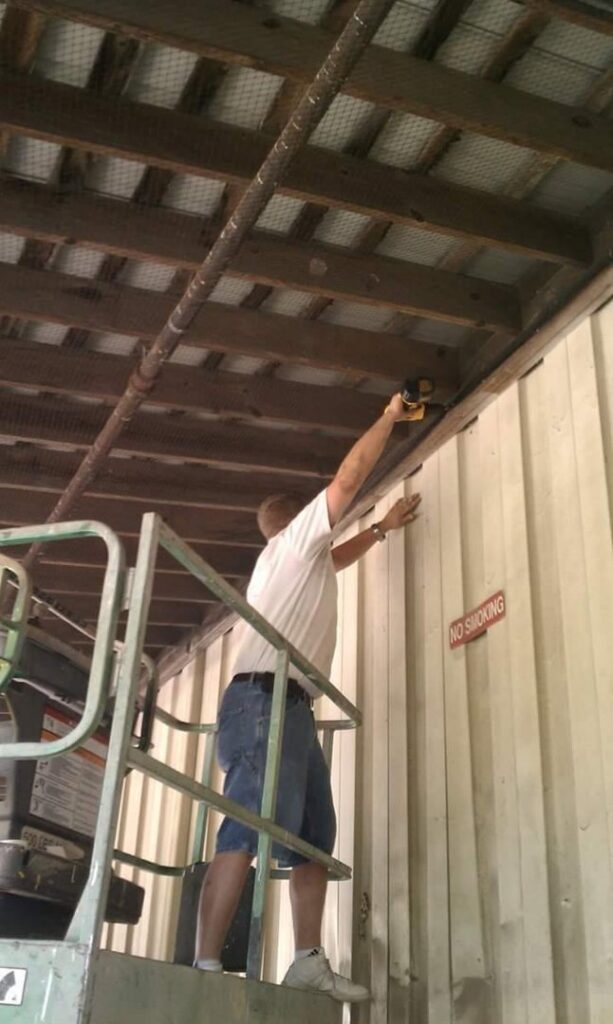 A D&J Pest Control technician in a scissor lift installing bird netting to prevent wildlife entry in Georgetown, KY.