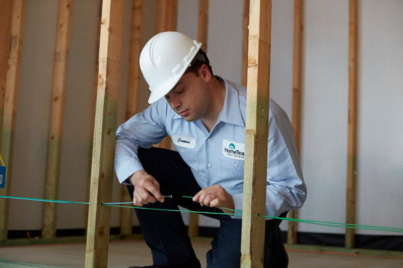 A HomeTeam Pest Defense technician installing a built-in pest control system in a wall frame in Longwood, FL.
