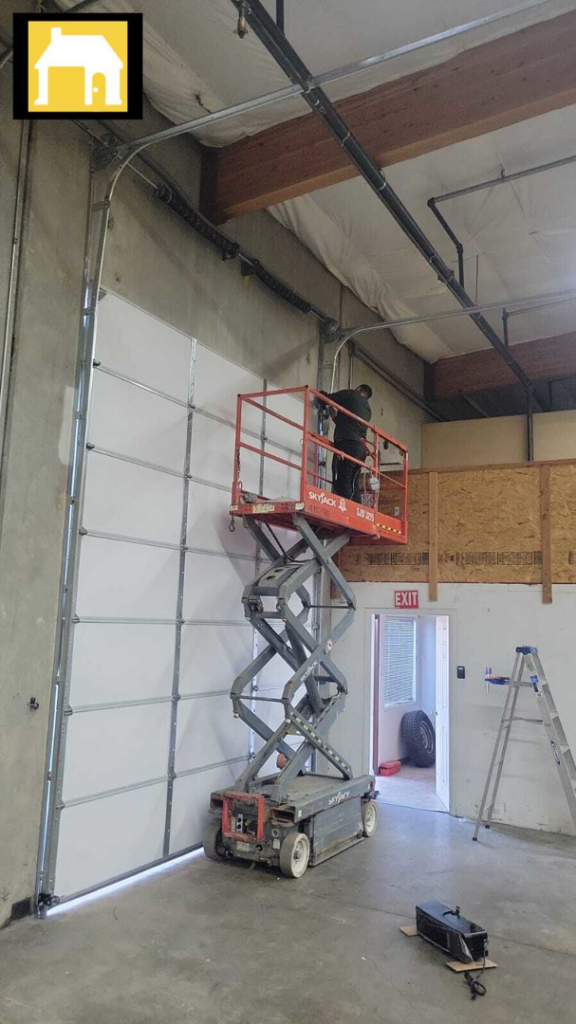 Technician installing a large commercial garage door from a scissor lift for TH Locksmith And Garage Door Repair, Vancouver, WA.