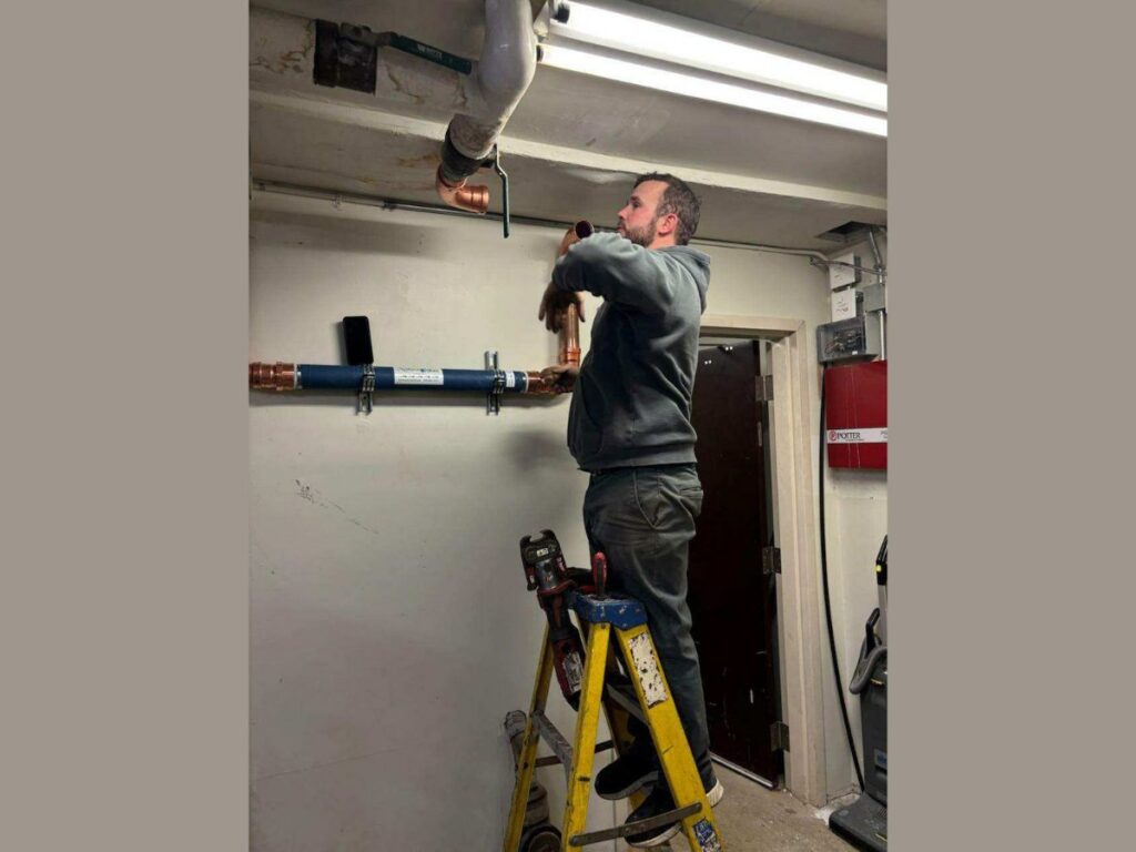 A technician installing copper pipes and lines on a ceiling for Thrasher Service Corp in Des Moines, IA.