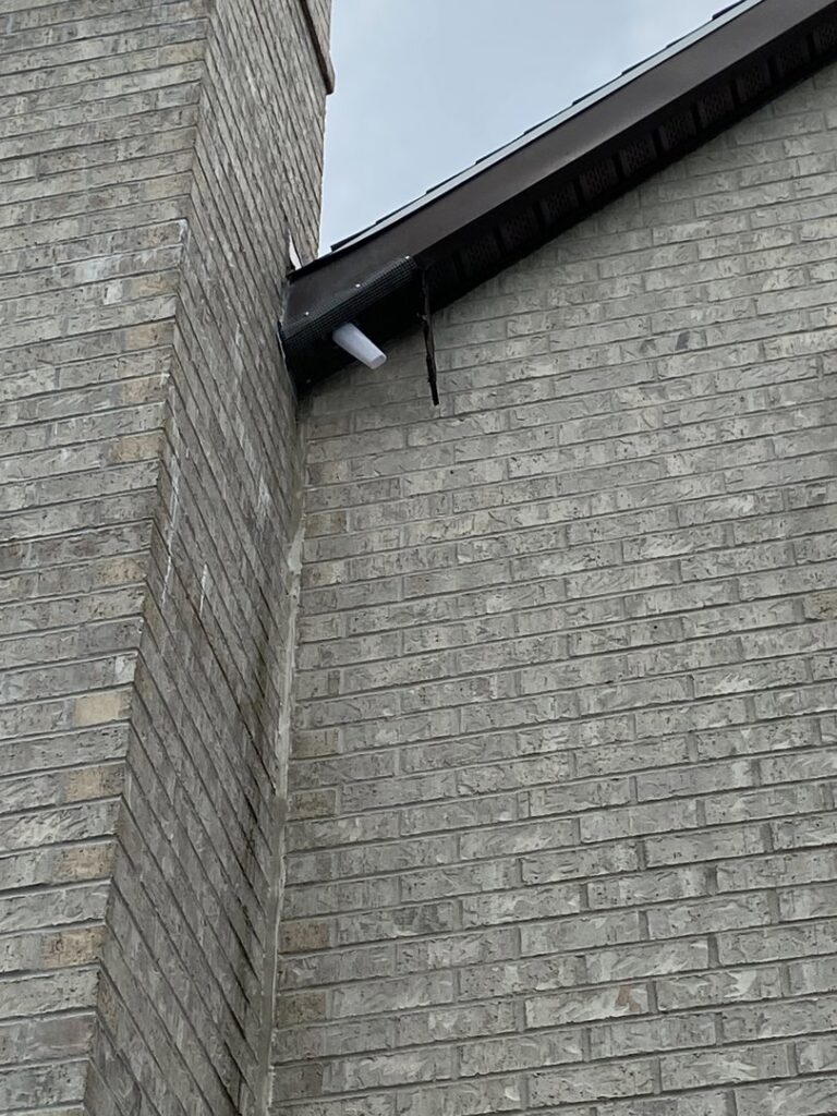 A technician installing a wire mesh exclusion barrier over a roof vent to prevent wildlife entry for Eagles Eye Wildlife in Waterbury, CT.