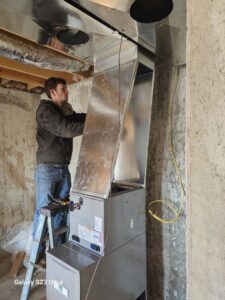 An HVAC technician installing a furnace and ductwork in a basement for Aces of Air Inc. in Georgetown, KY.