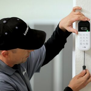 A technician installing a garage door keypad and camera system for American Overhead Door in Madison, AL