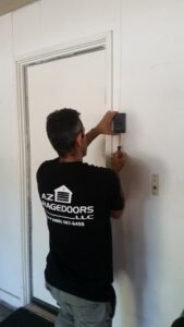 A technician from Az Garage Door installing or repairing a garage door opener control panel in Phoenix, AZ.