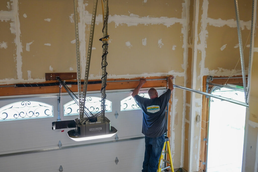 A Prutch's Garage Door technician installing a garage door opener and track system in a residential garage in Colorado Springs, CO