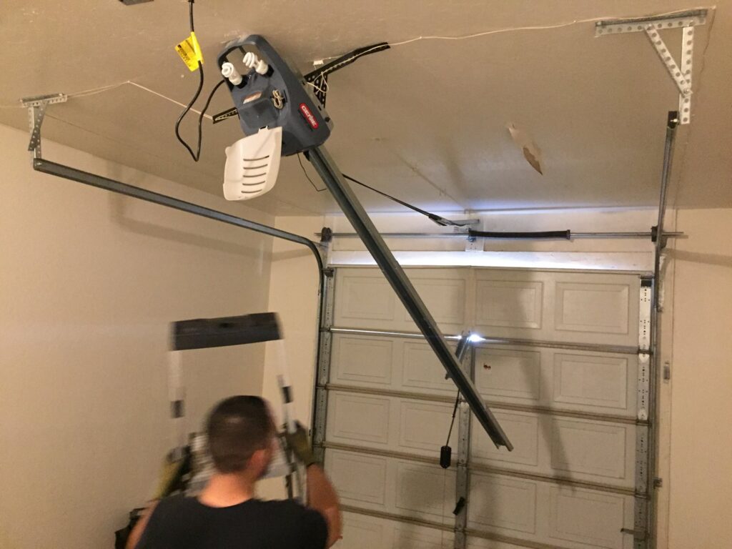 A technician installing a garage door opener and rail for Nate's Garage Door Repair in Scottsdale, AZ.