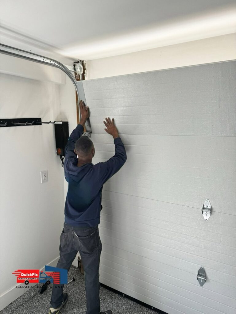 A technician installing a garage door panel as part of a new installation by QuickFix Garage Door Service in Brighton, MA.