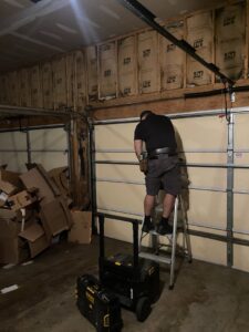 A technician on a ladder installing garage door panels for The Region's Garage Door Repair in Hammond, IN.