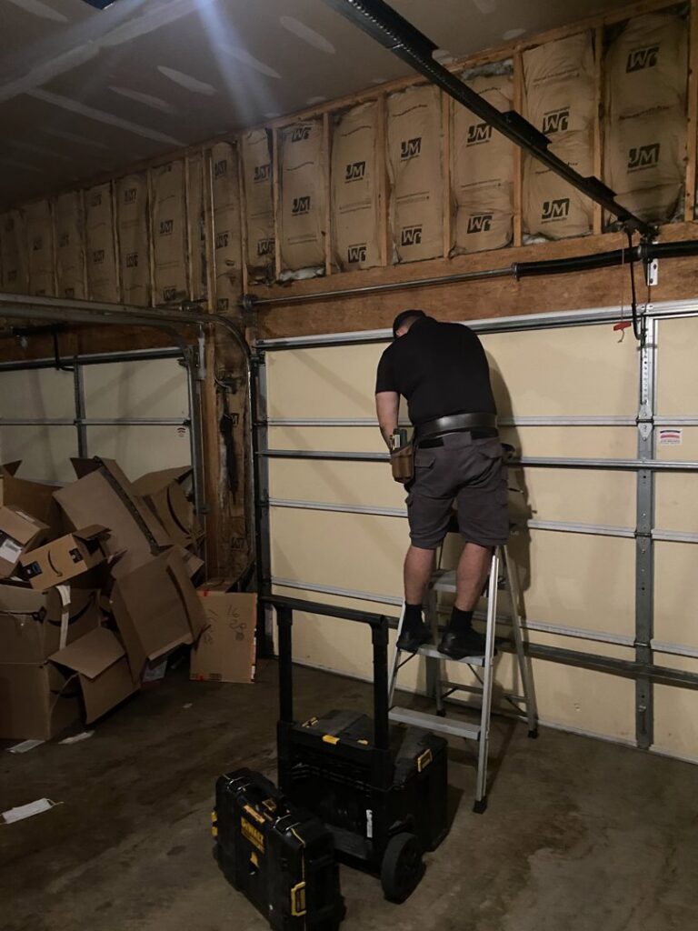 A technician on a ladder installing garage door panels for The Region's Garage Door Repair in Hammond, IN.