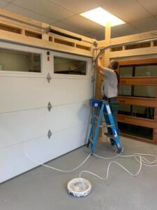 A technician from 314 Overhead Doors on a ladder installing garage door tracks and springs in O'Fallon, MO.