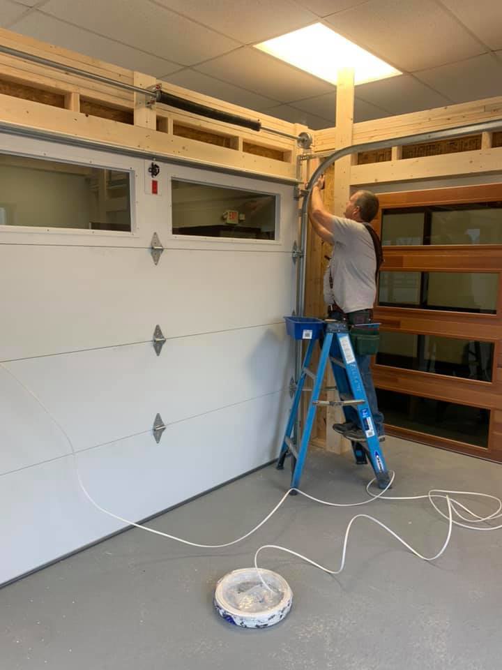 A technician from 314 Overhead Doors on a ladder installing garage door tracks and springs in O'Fallon, MO.