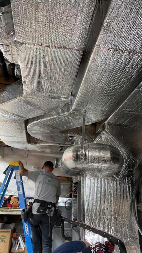 A technician installing an HVAC air handler and ductwork in a basement for Ultra Installs in Barrington, NH