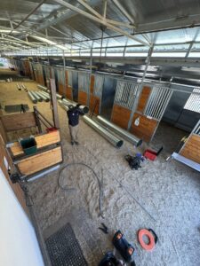 A technician installing large HVAC ductwork in a commercial or industrial setting for Blue Collar Mechanical LLC in Indianapolis, IN.