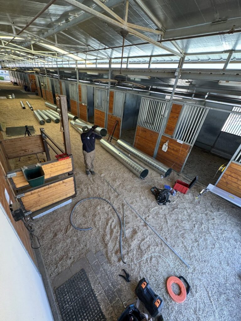 A technician installing large HVAC ductwork in a commercial or industrial setting for Blue Collar Mechanical LLC in Indianapolis, IN.
