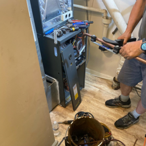 A technician installing or repairing an HVAC furnace and copper lines for Doctor Air HVAC in Philadelphia, PA.