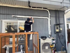 A Fix It Now Heating and Cooling technician installing outdoor HVAC piping or conduit on a building in Thornton, CO
