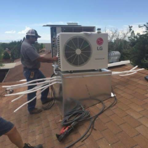 A King's Mechanical technician installing an outdoor HVAC unit on a rooftop in Alamogordo, NM.