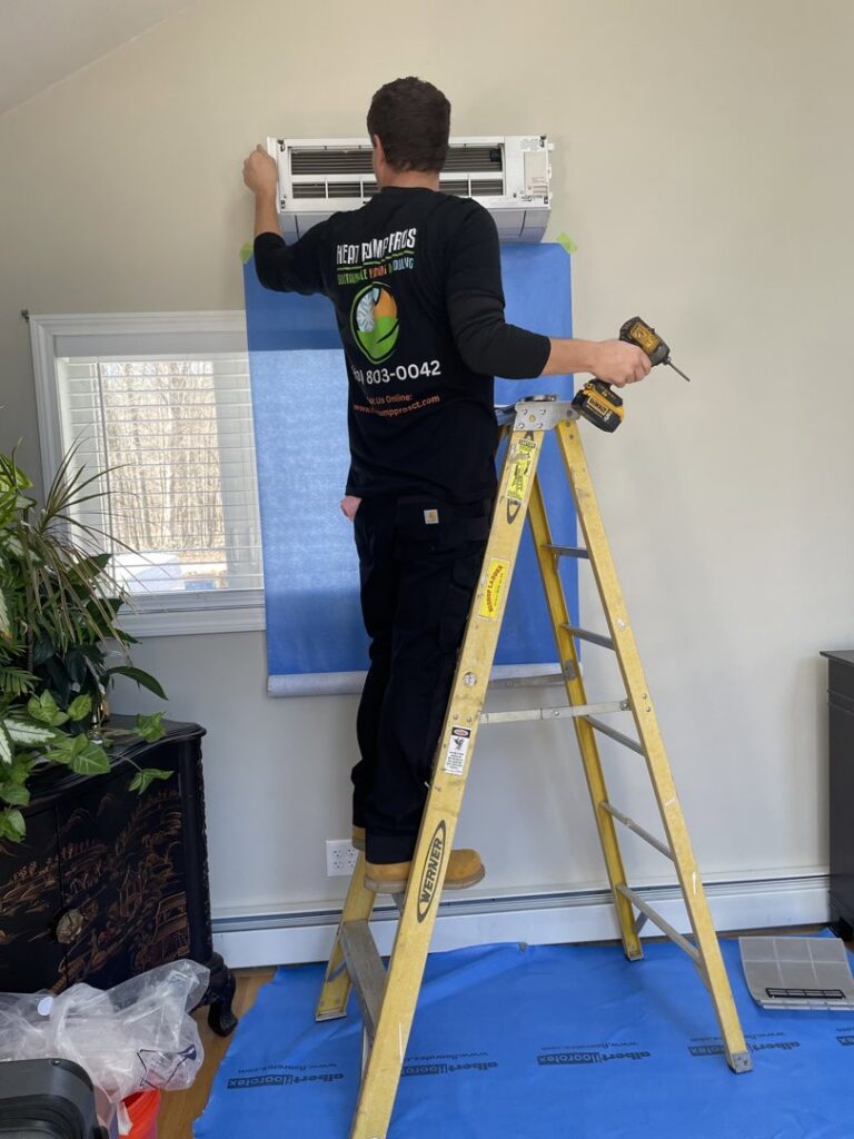 A Heat Pump Pros technician installing an indoor mini-split heat pump unit on a wall in Hartford, CT.