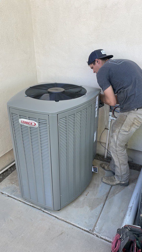 A Hicken Air technician installing or servicing a new Lennox outdoor HVAC unit at a residence in Gilbert, AZ