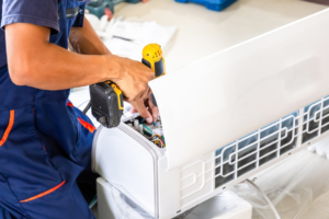 A technician installing or repairing an indoor mini-split air conditioning unit for Chrismon Heating & Cooling in Greensboro, NC.