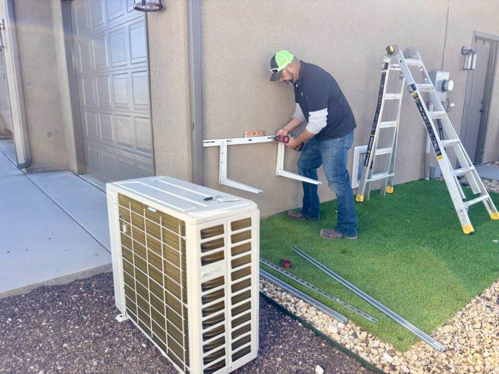 A technician from Lee's Heating & Cooling installing mounting brackets for a mini-split outdoor unit in Pueblo, CO.