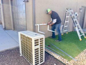 A technician from Lee's Heating & Cooling installing mounting brackets for a mini-split outdoor unit in Pueblo, CO.