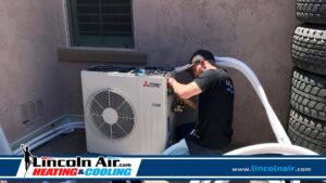 A Lincoln Air & Plumbing technician installing or repairing a Mitsubishi Electric mini-split condenser unit in Phoenix, AZ