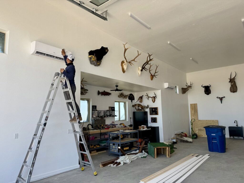 A technician installing a mini-split indoor unit in a garage by Mi Amigo HVAC in Surprise, AZ