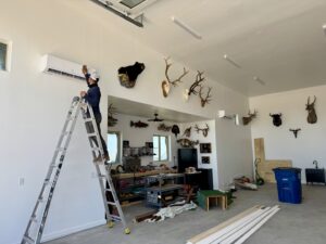 A technician installing a mini-split indoor unit in a garage by Mi Amigo HVAC in Surprise, AZ