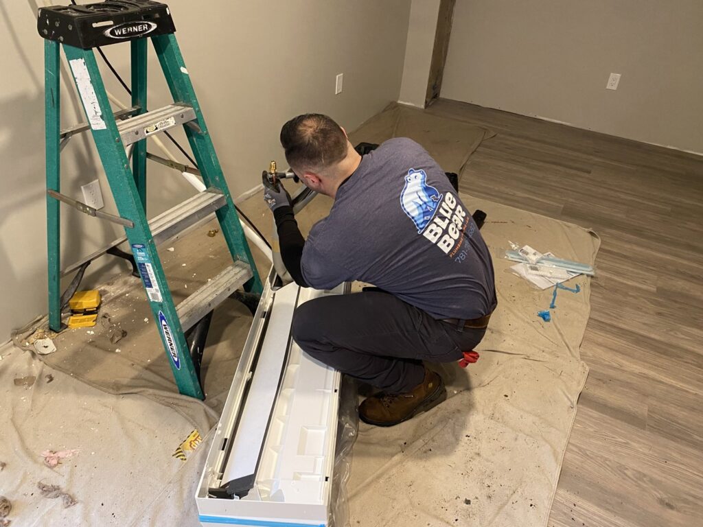 A Blue Bear Plumbing, Heating, & Air technician installing an indoor mini-split air conditioning unit in Norwell, MA.
