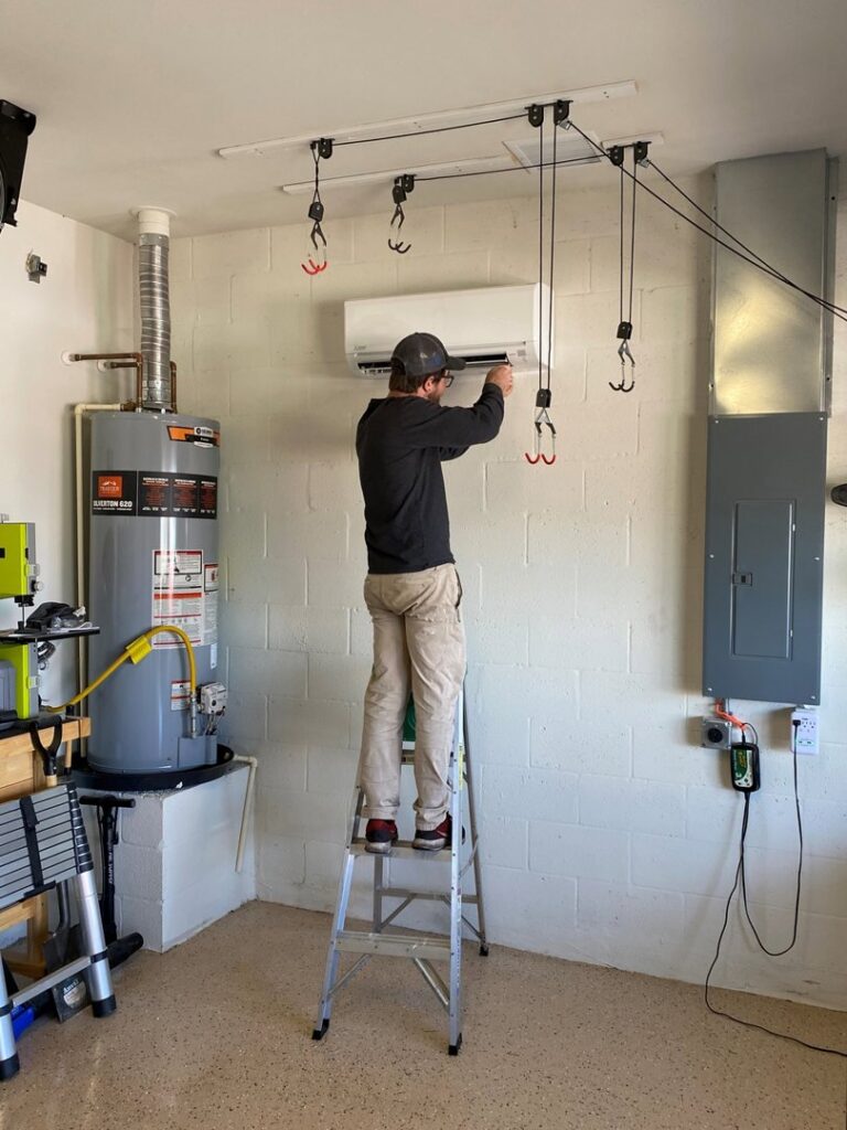 A Coral Air Conditioning technician installing a ductless mini-split indoor unit in a garage in Cape Coral, FL.