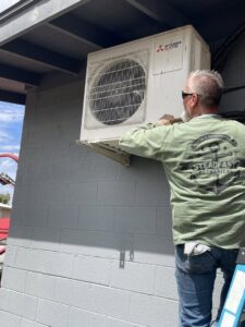 A Steadfast Mechanical technician installing a wall-mounted mini-split outdoor unit in Gilbert, AZ.