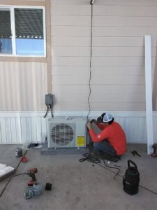 A technician installing or servicing an outdoor mini-split HVAC unit for Heating & Air Paramedics - Tucson in Tucson, AZ.