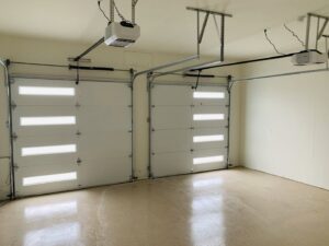 An IGD Garage Door Repair technician on a ladder installing a new garage door on a house under construction in Renton, WA.