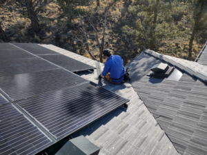 A Solid Pest Solutions technician installing pest exclusion mesh under solar panels on a roof in Bend, OR.