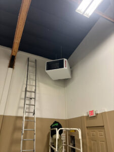 A Gagles Heating technician installing a Reznor unit heater in a commercial building in Salem, OR.